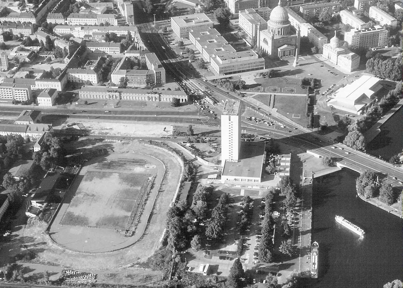 Foto: Historisches Luftbild des Lustgartens mit Nutzung als Stadion. Im Bereich des ehemaligen Neptunbassins findet sich ein großer Parkplatz.