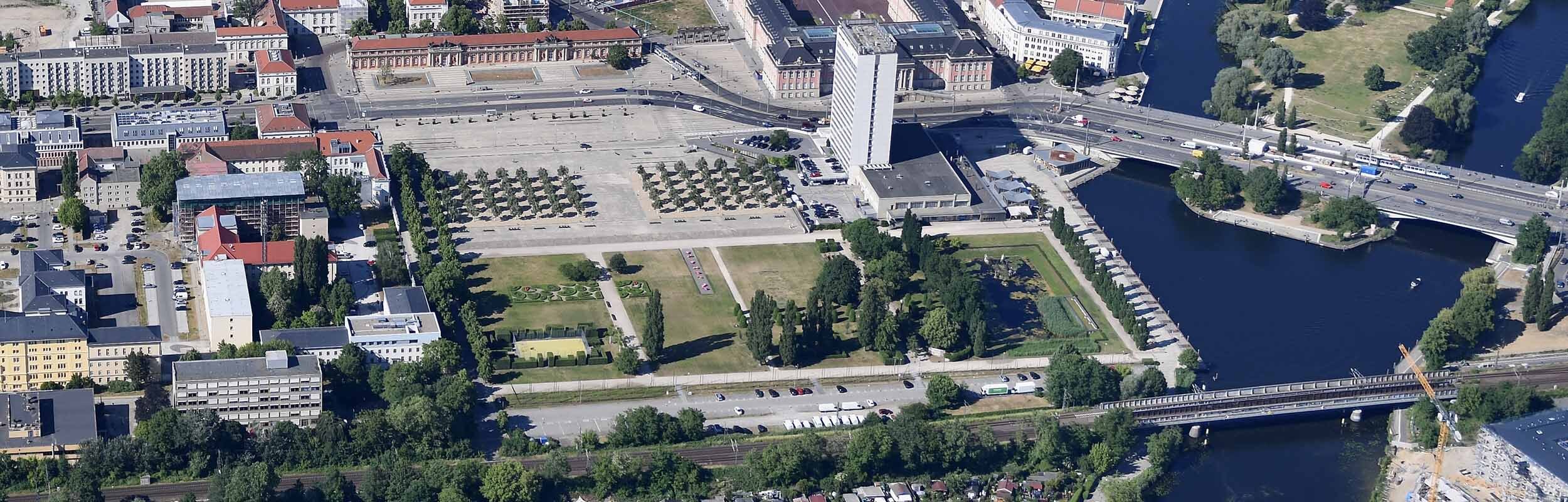 Foto: Luftbild des begrünten Lustgartens mit Neptunbassin im Osten und großzügigem Stadtplatz im Norden. Des Weiteren zusehen sind die Lange Brücke, der Landtag, das Mercure Hotel, sowie das Filmmuseum.